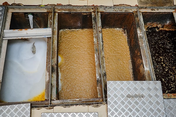 grease trap maintenance typically involves manual scraping, pressure washing, and vacuuming to remove grease and buildup